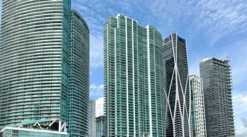 Multi-story residential buildings with modern glass facades against a blue sky.